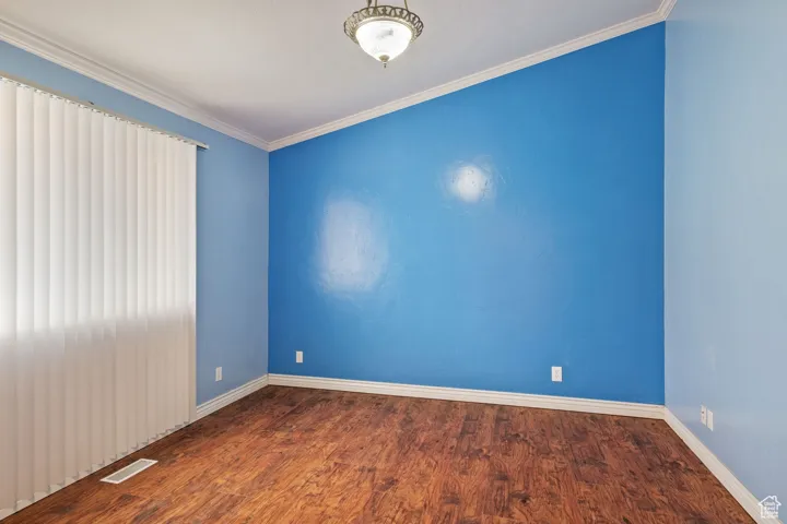 Spare room with visible vents, wood finished floors, ornamental molding, and baseboards