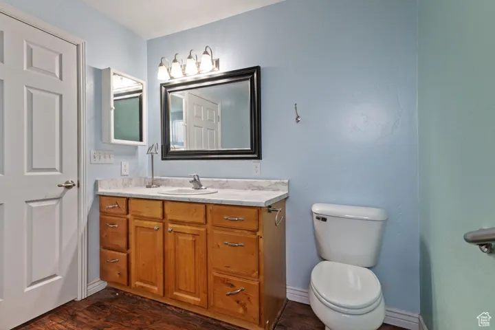 Bathroom featuring wood finished floors, toilet, and vanity