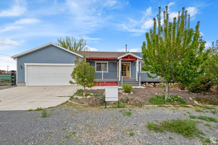 Ranch-style house featuring driveway, a garage, stucco siding, and covered porch