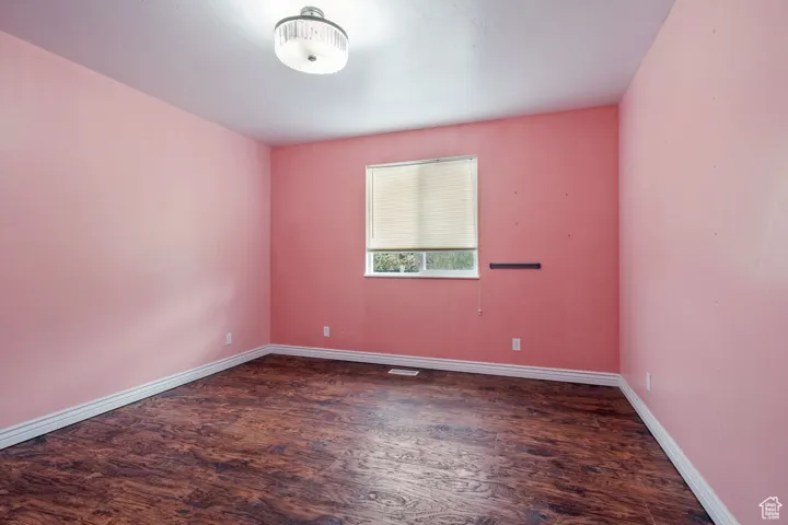 Empty room featuring visible vents, wood finished floors, and baseboards