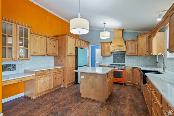 Kitchen featuring tasteful backsplash, freestanding refrigerator, ornamental molding, high end stainless steel range oven, and premium range hood