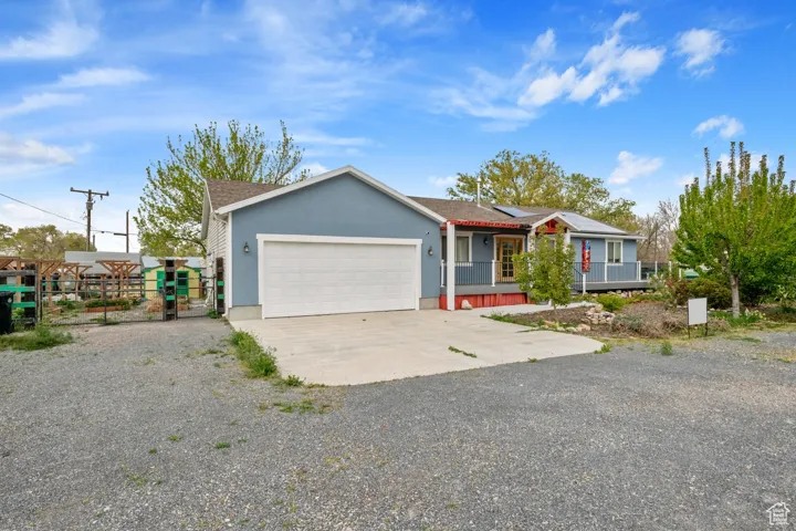 Ranch-style home with stucco siding, roof mounted solar panels, concrete driveway, an attached garage, and fence