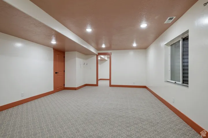 Finished below grade area featuring recessed lighting, a textured ceiling, light colored carpet, and baseboards