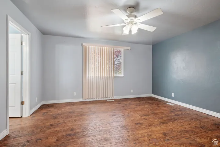 Empty room with visible vents, ceiling fan, wood finished floors, and baseboards