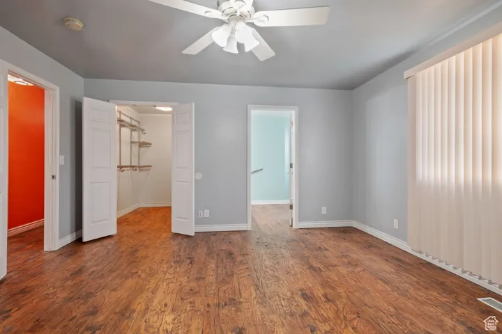 Unfurnished bedroom featuring visible vents, a closet, baseboards, wood finished floors, and a walk in closet