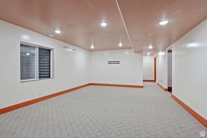 Unfurnished room with recessed lighting, a textured ceiling, light colored carpet, and baseboards