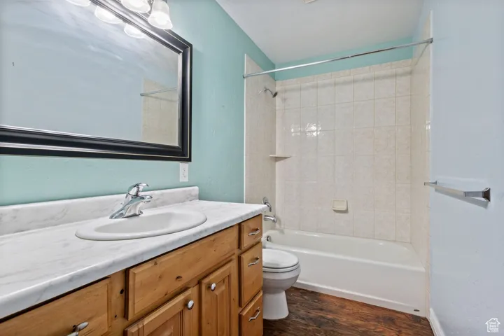Bathroom featuring wood finished floors, toilet, washtub / shower combination, and vanity