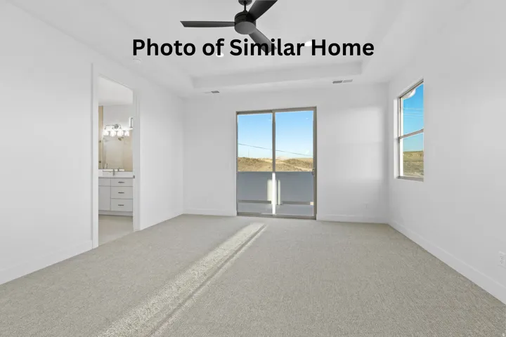 Unfurnished bedroom with light colored carpet, a tray ceiling, access to outside, ensuite bathroom, and a ceiling fan