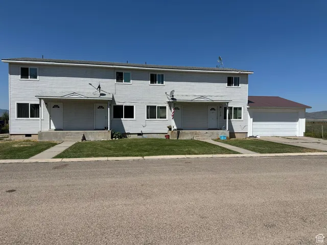 Traditional home featuring covered porch, driveway, an attached garage, and a front lawn