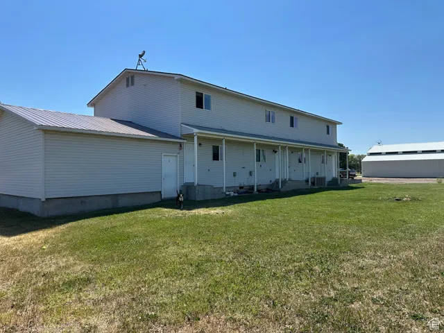 Back of house with a lawn and a metal roof
