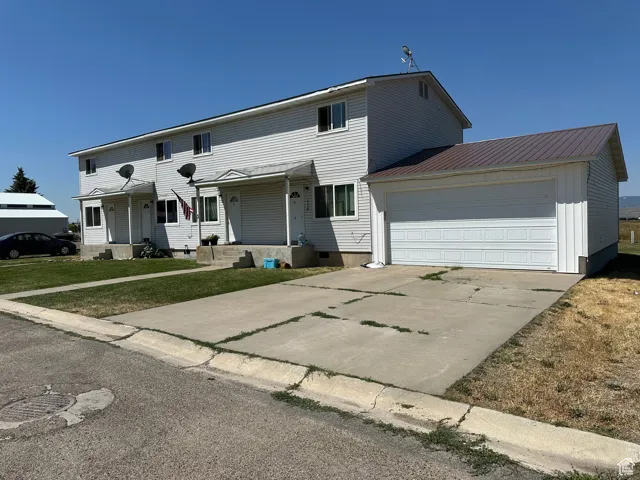 View of front facade featuring an attached garage, concrete driveway, crawl space, a metal roof, and a porch