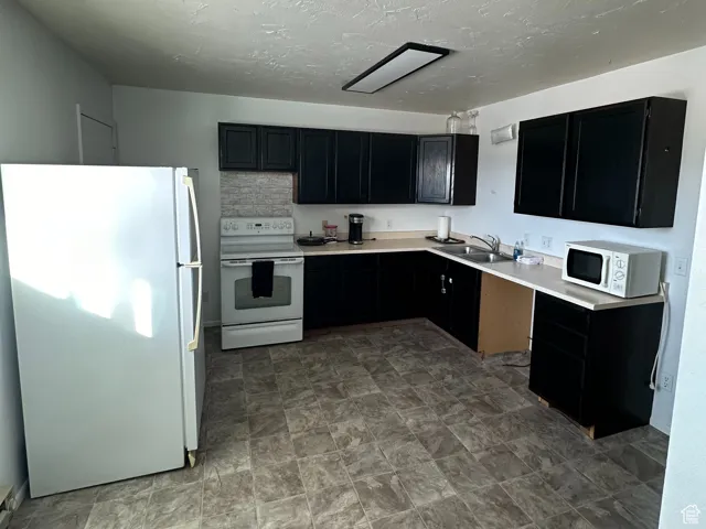 Kitchen with a textured ceiling and white appliances
