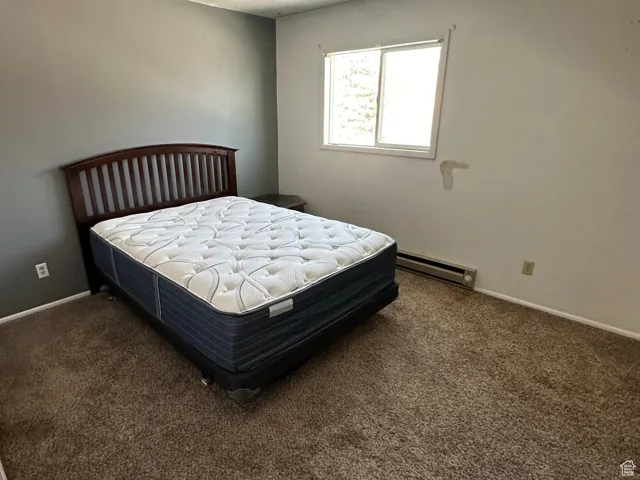 Carpeted bedroom with a textured ceiling and a baseboard heating unit