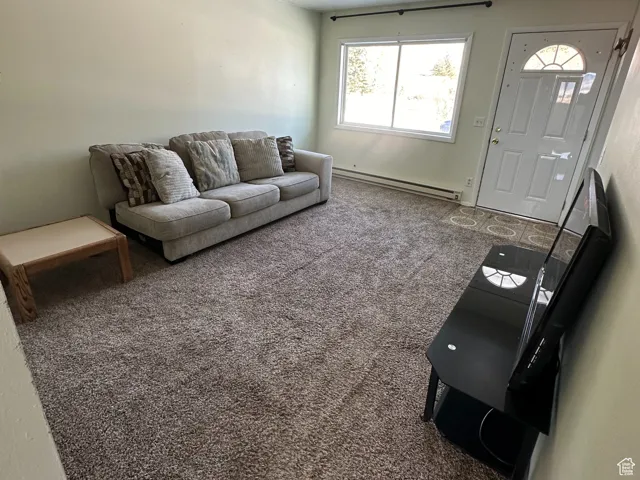 Carpeted living room featuring a textured ceiling and baseboard heating