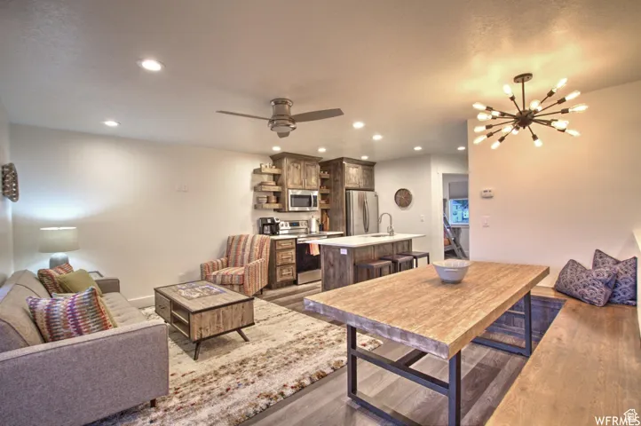 Living room with dark hardwood / wood-style flooring, ceiling fan with notable chandelier, and sink