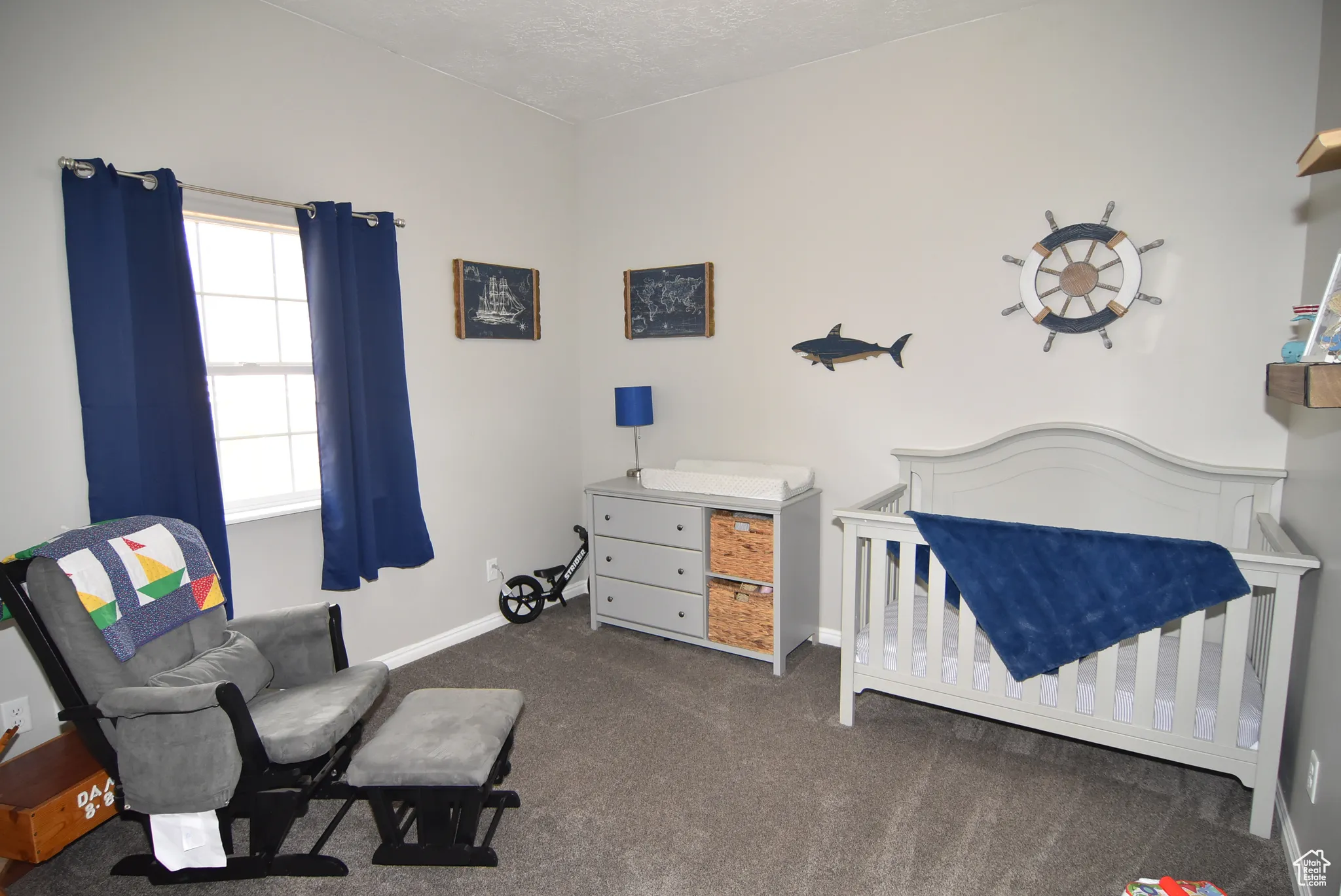 Carpeted bedroom with a textured ceiling and a crib