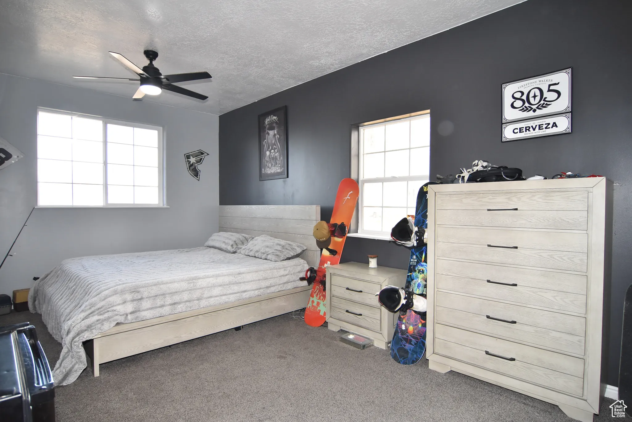 Bedroom with ceiling fan, a textured ceiling, and dark colored carpet