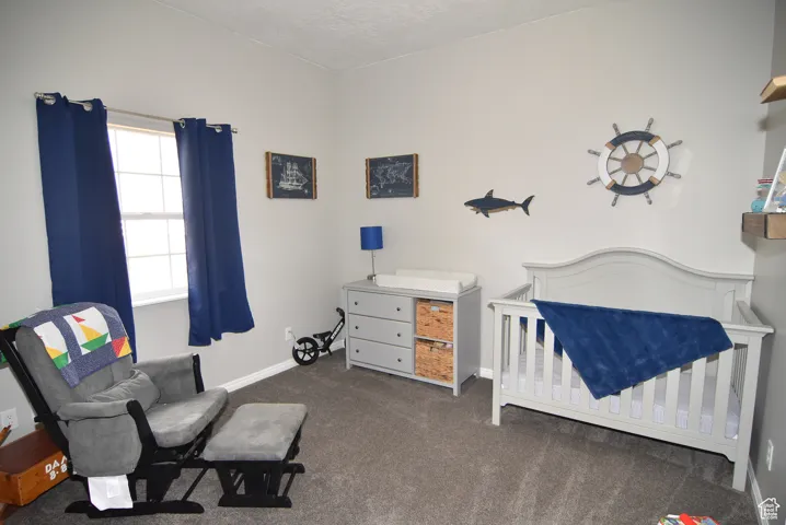 Carpeted bedroom with a textured ceiling and a crib
