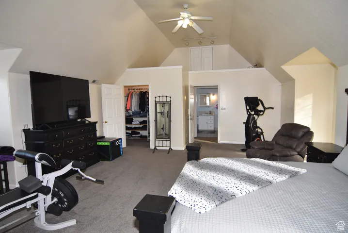 Carpeted bedroom featuring connected bathroom, ceiling fan, lofted ceiling, a walk in closet, and a closet