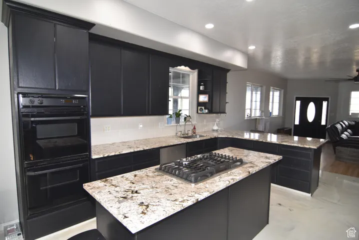 Kitchen with sink, stainless steel appliances, kitchen peninsula, decorative backsplash, and a kitchen island