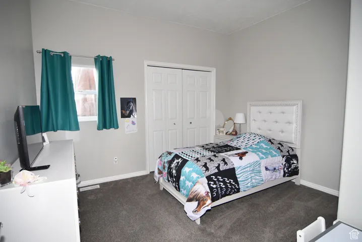 Bedroom with dark carpet and a closet