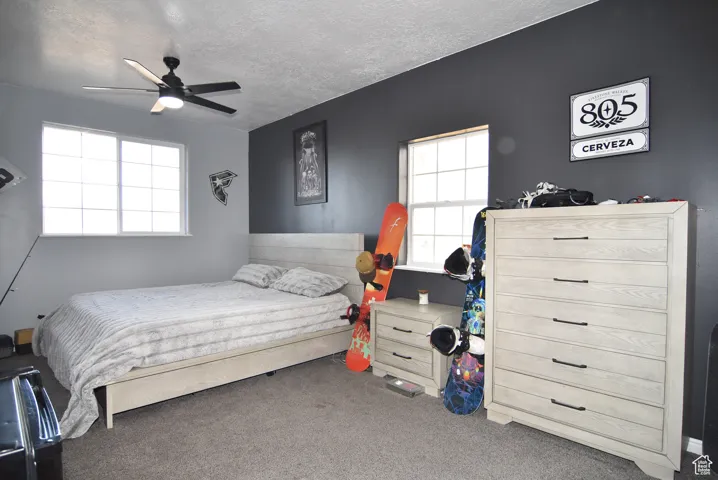 Carpeted bedroom with ceiling fan and a textured ceiling