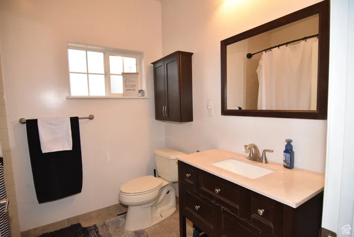 Bathroom with tile patterned flooring, vanity, toilet, and curtained shower