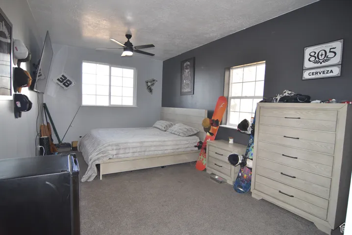 Bedroom featuring carpet, ceiling fan, and a textured ceiling