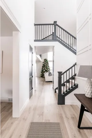 Two-story entry foyer featuring wood-finish flooring, white walls with wainscoting, and a staircase with dark balusters and handrails