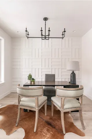Feature wall with geometric paneling, light wood-finish flooring, and a contemporary black chandelier