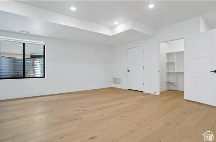 Unfurnished bedroom featuring a walk in closet and light wood-type flooring