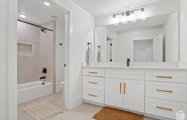 Full bathroom featuring vanity, tile patterned flooring, tiled shower / bath combo, and toilet