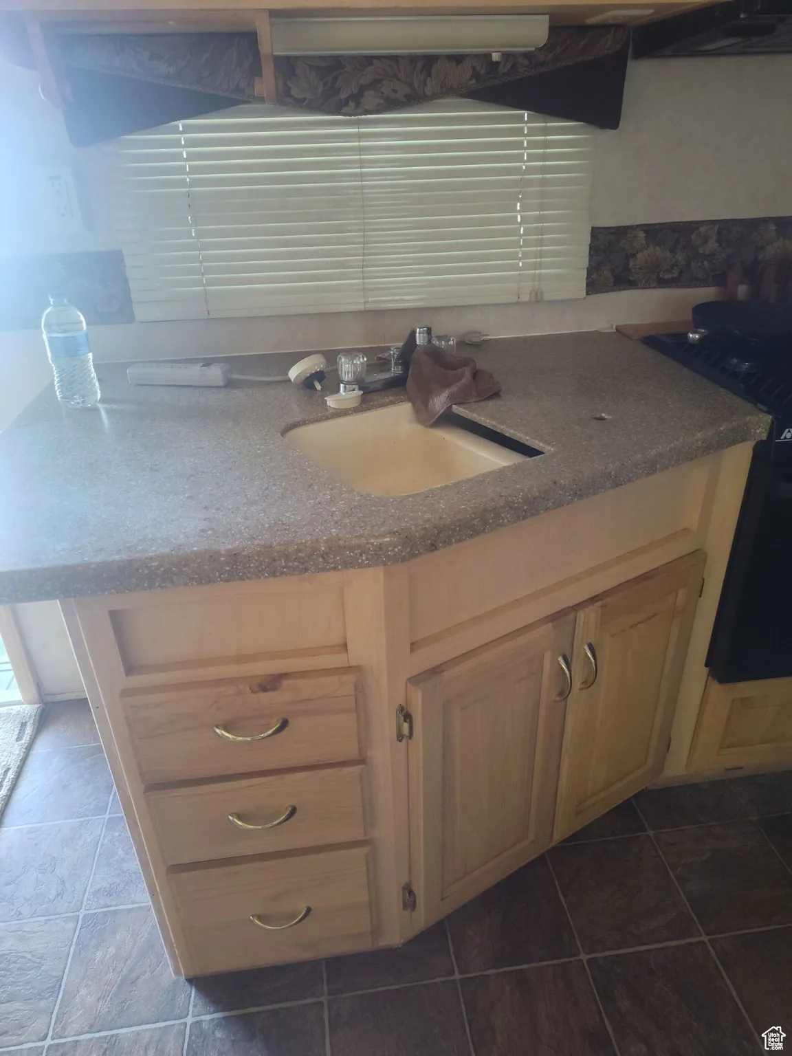 Kitchen with light brown cabinets, dark tile patterned floors, and sink