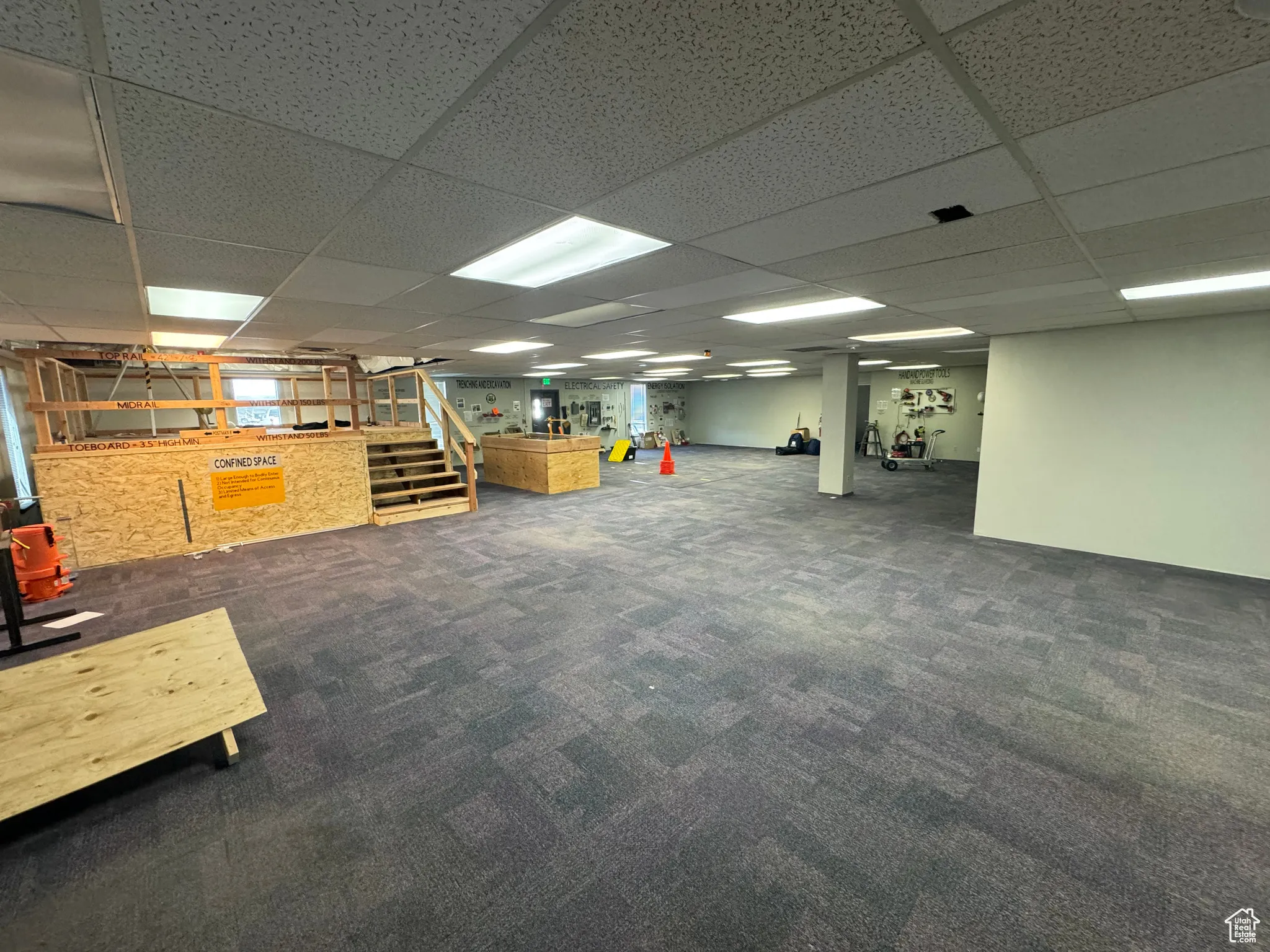 Basement with dark colored carpet and a drop ceiling