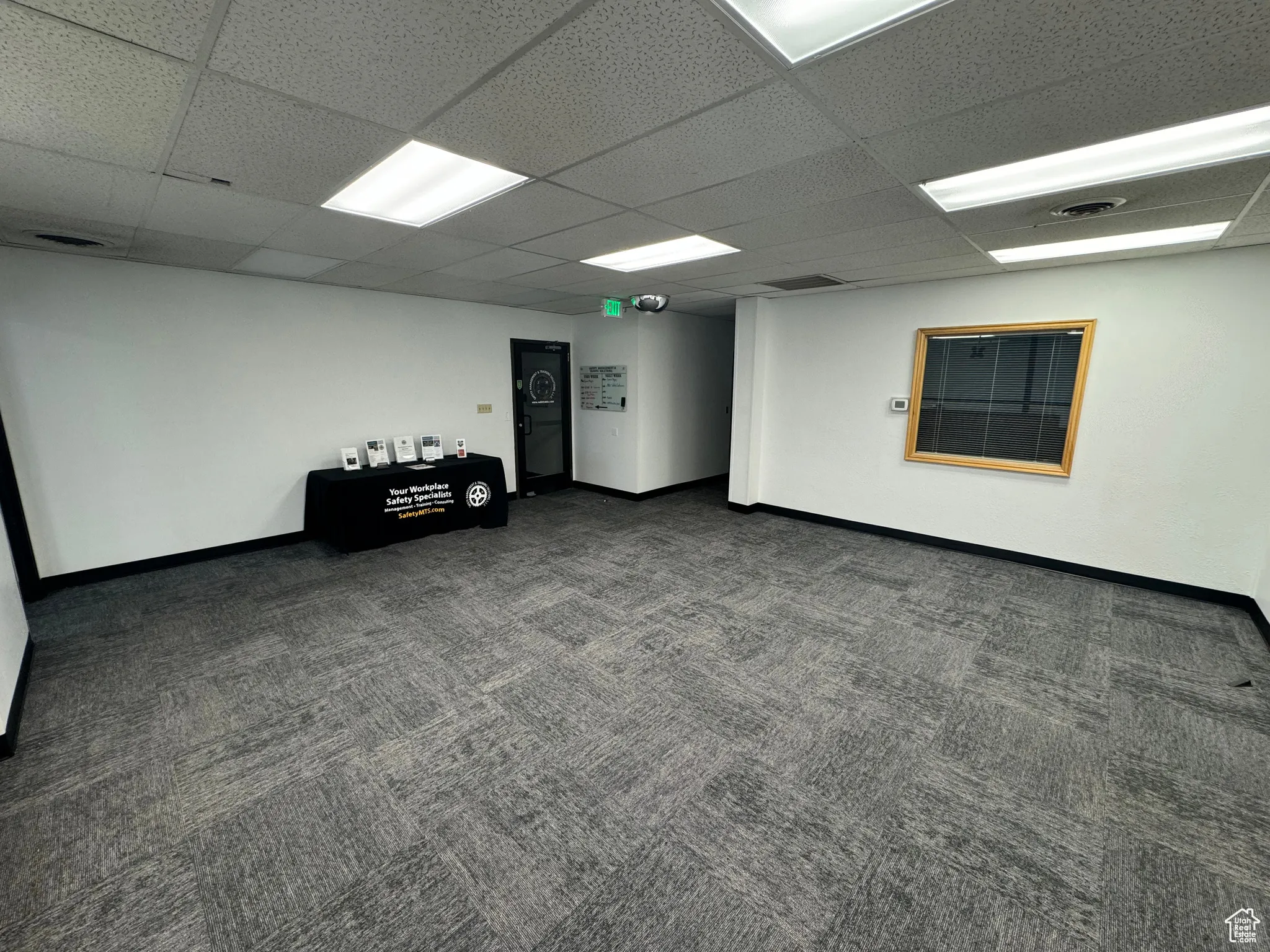 Empty room featuring dark colored carpet and a paneled ceiling