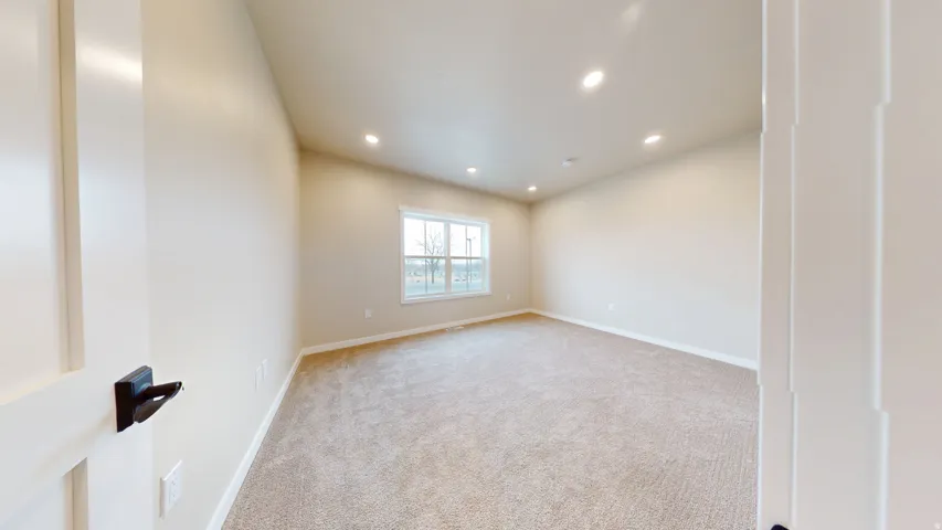 Empty room featuring recessed lighting and light carpet