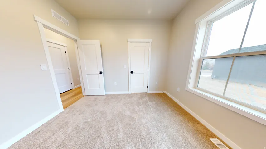 Unfurnished bedroom featuring light colored carpet and baseboards