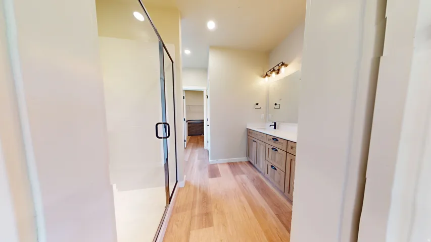 Bathroom with light wood-style floors, vanity, recessed lighting, and a shower stall