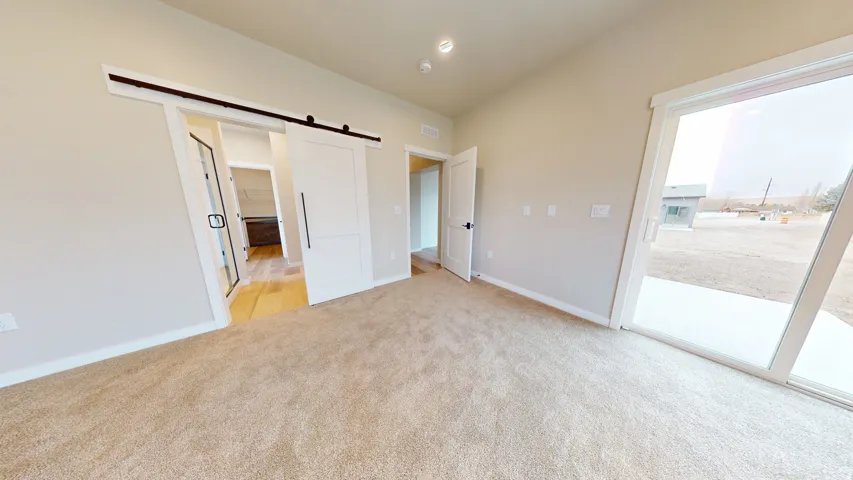 Unfurnished bedroom featuring a barn door, access to outside, and light colored carpet