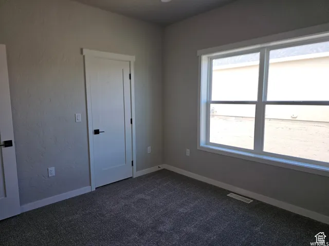 Unfurnished room featuring dark carpet