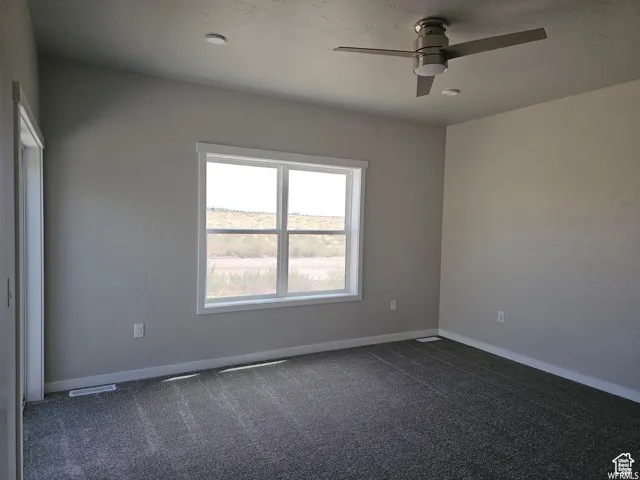 Carpeted empty room featuring ceiling fan