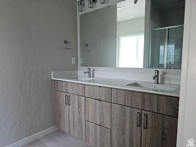 Bathroom with vanity, a shower with shower door, and hardwood / wood-style flooring