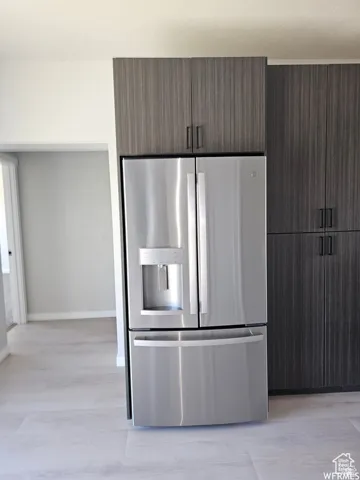 Kitchen with dark brown cabinets, light hardwood / wood-style floors, and stainless steel refrigerator with ice dispenser