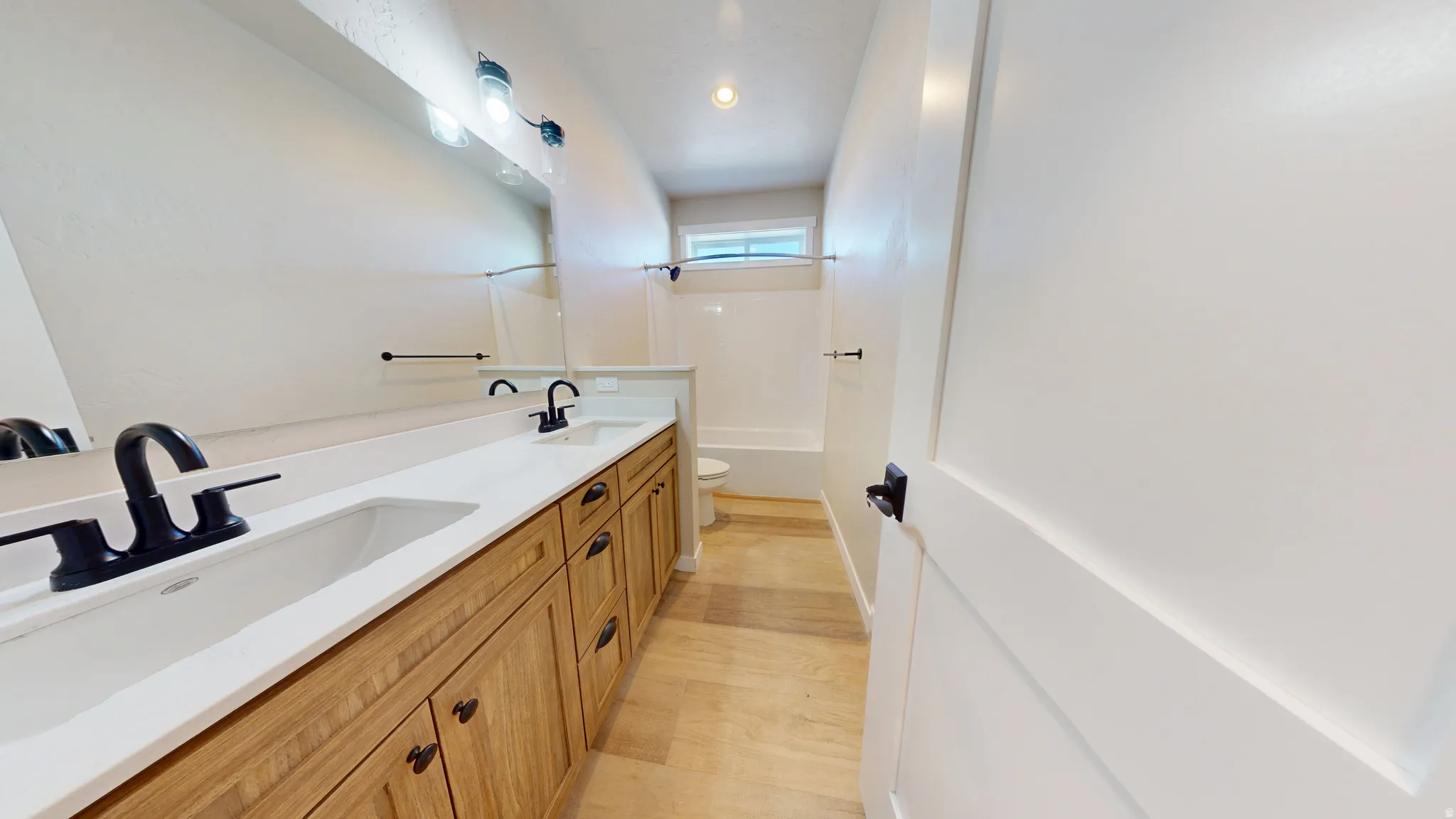 Full bathroom with double vanity, light wood finished floors, and bathing tub / shower combination