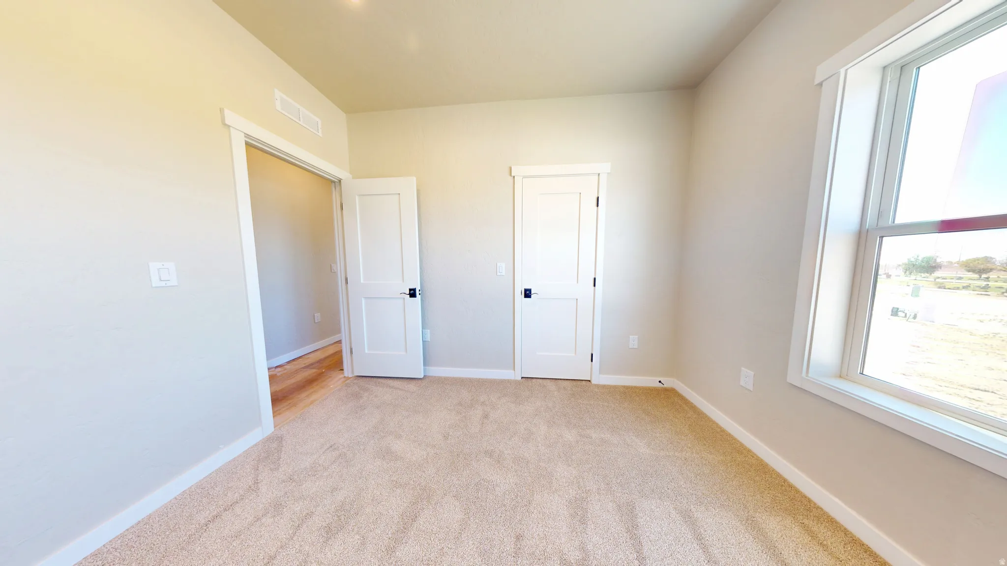 Unfurnished bedroom featuring light carpet and baseboards