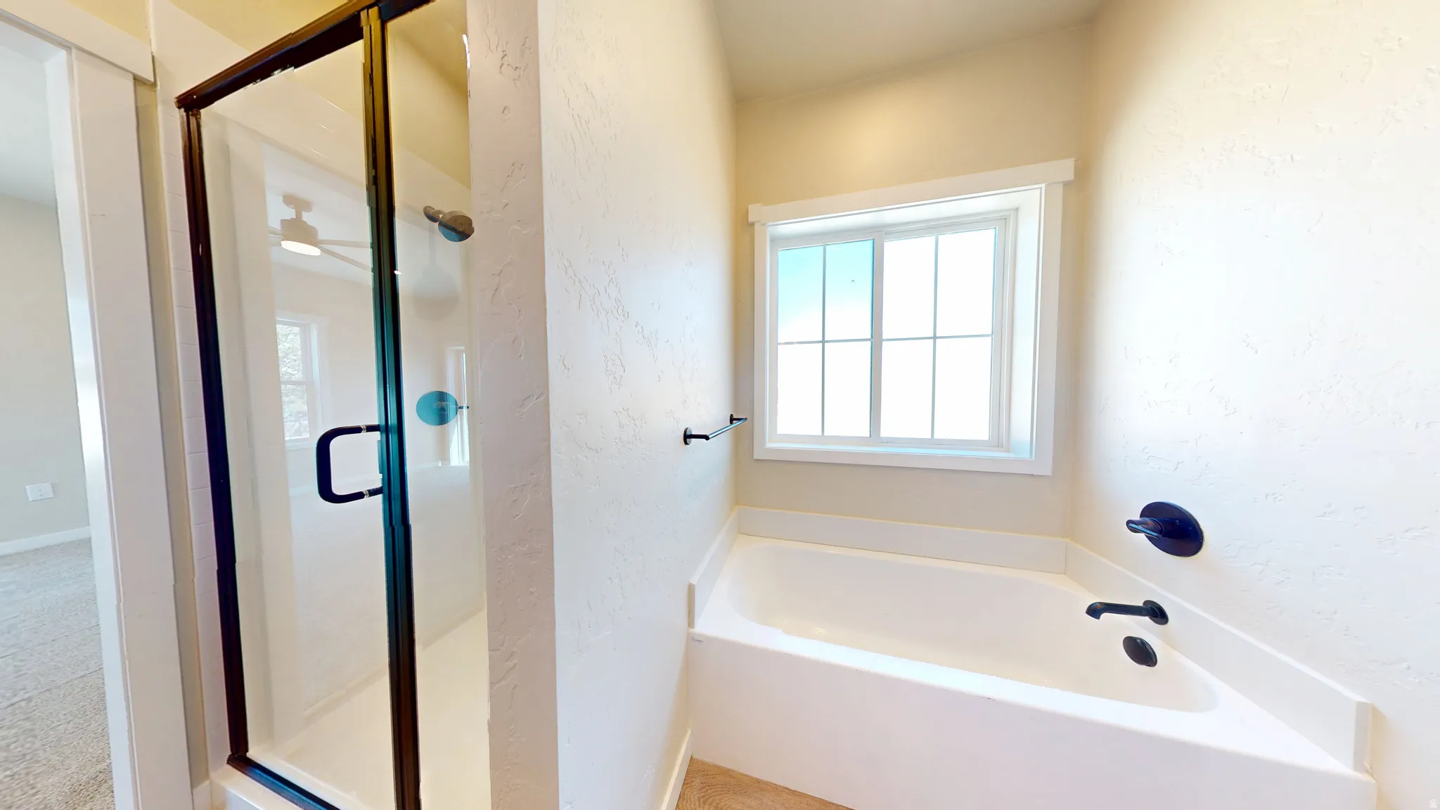 Bathroom with a textured wall, a shower stall, and a garden tub