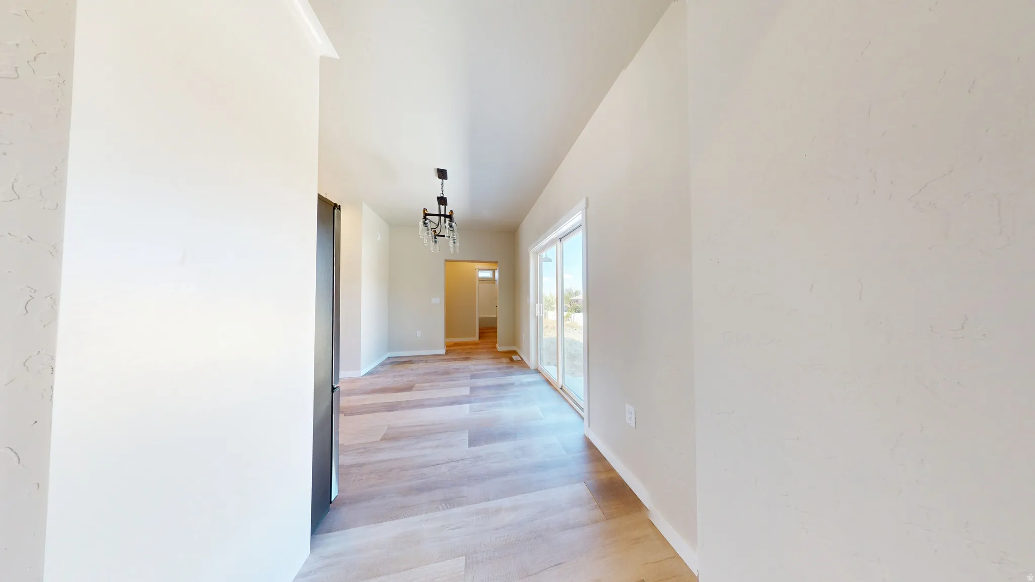 Corridor featuring light wood-style flooring and a chandelier