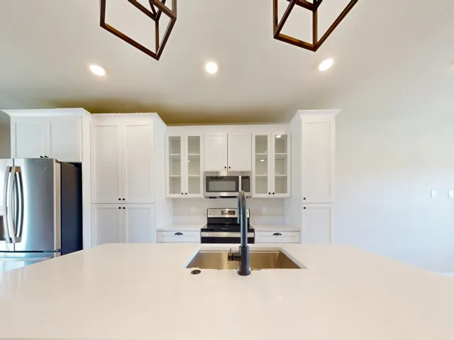 Kitchen with glass insert cabinets, recessed lighting, appliances with stainless steel finishes, white cabinets, and a kitchen island with sink