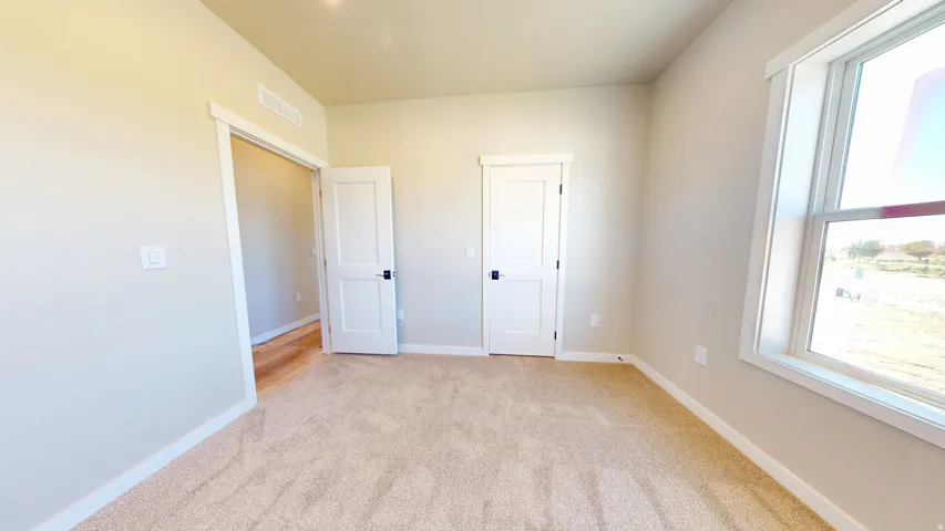 Unfurnished bedroom featuring light carpet and baseboards