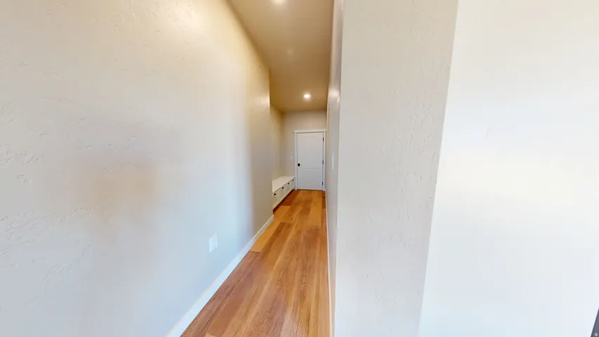 Hallway featuring light wood finished floors and a textured wall